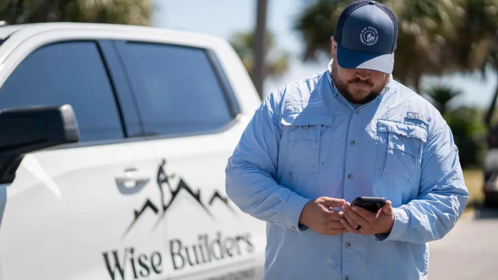 the owner of wise builders roofing and renovations on the phone checking on the cost of roof repair costs in mobile al