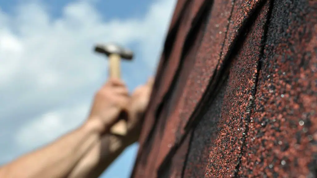 using a hammer and nail to instal a replacement shingle