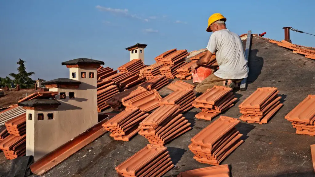 a roofer installing orange cement tiles on a roof