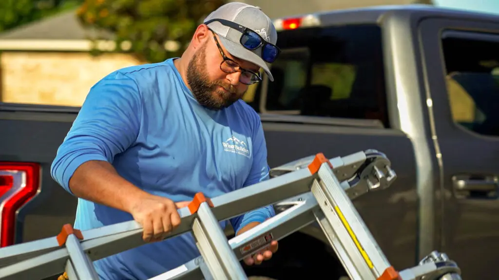 a roofer ready to use his ladder on a shingle roof