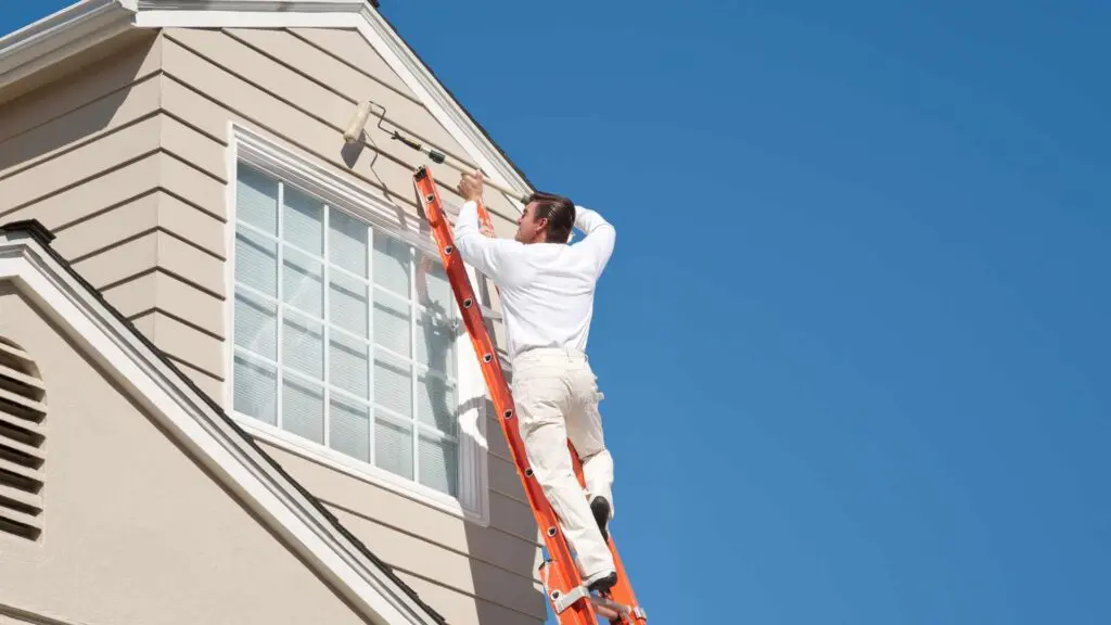 a painter using an extension ladder to reach up high