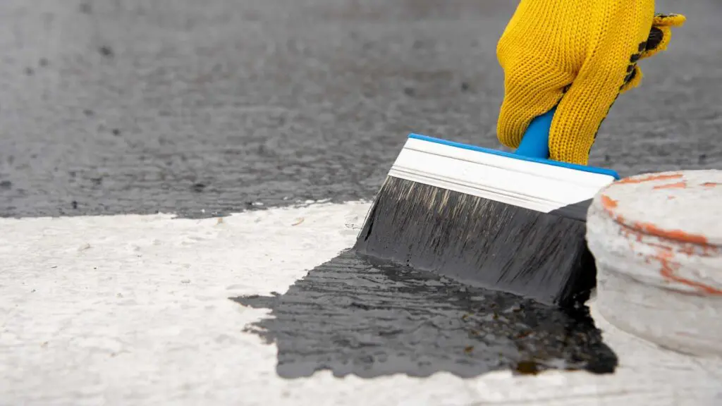 a waterproof membrane being painted on a roof with a bruch