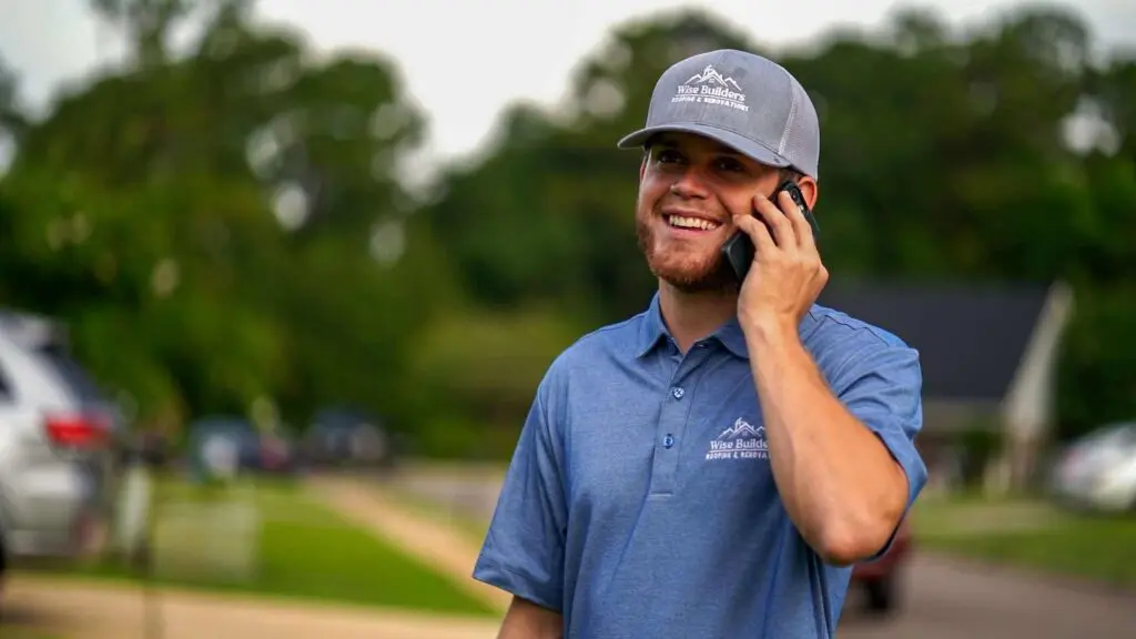 a roofer from wise builders roofing and renovation son the phone with insurance companies going over a clients insurance policy