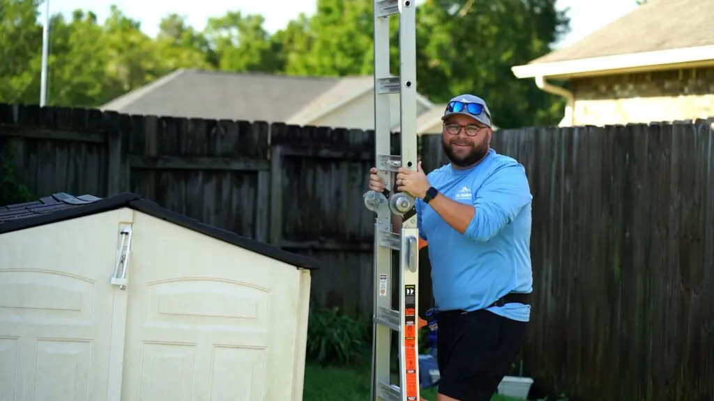 a project manager from wise builders roofing and renovations holding a ladder to help with a roof replacement