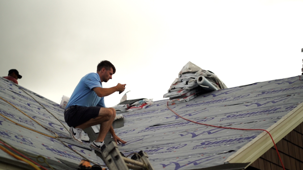 a roofer taking photos of a new roof being installed in cold weather
