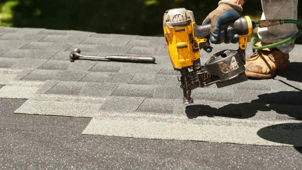 a roofer performing a roof replacement using a nail gun