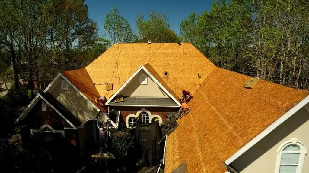 roofers preparing to install new shingles on plywood
